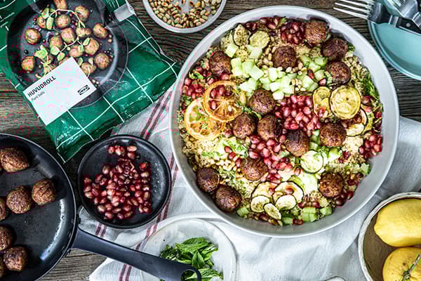 Eine Schüssel mit Couscous Salat mit Minze steht neben verschiedenen Zutaten.