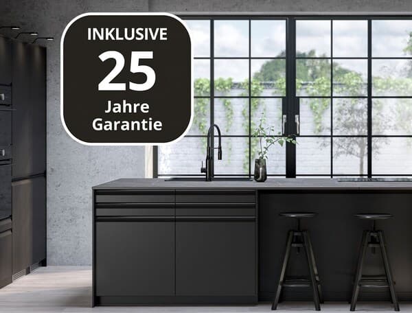 Eine schwarze großzügig gestaltete Küche mit einer Fensterfront. Im Vordergrund sieht man das Garantielogo für 25 Jahre