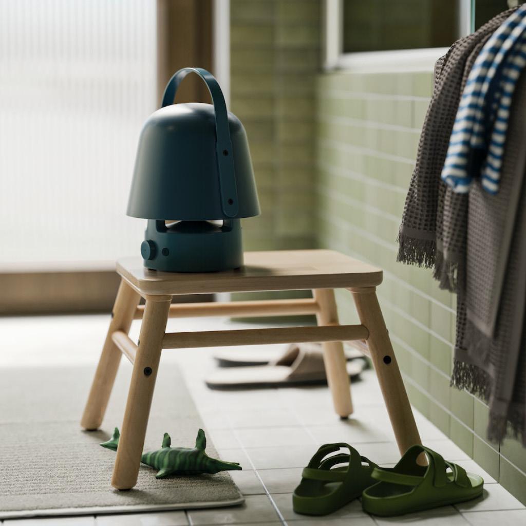 Eine schwarze VAPPEBY Lautsprecherleuchte steht auf einem Hocker im Badezimmer