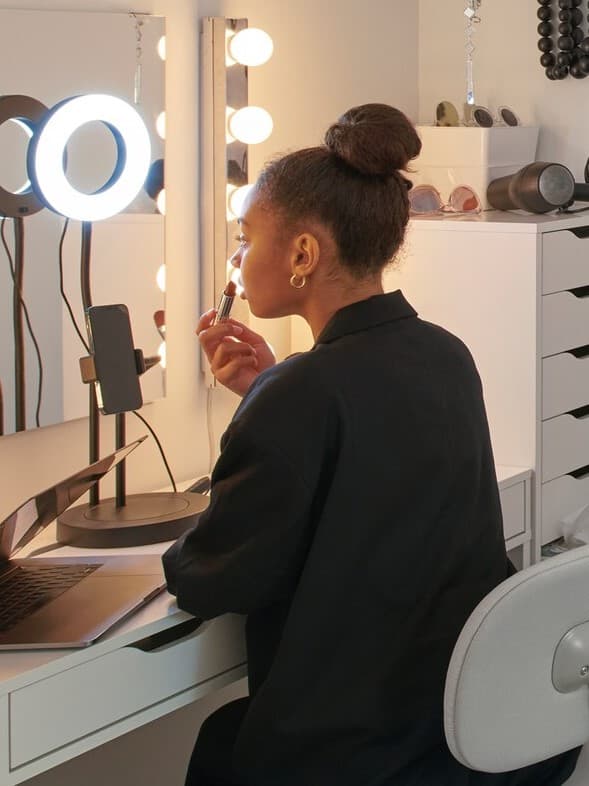 Eine Studentin mit langen Haaren sitzt in einem Wohnheimzimmer auf einem BLECKBERGET Drehstuhl an einem MICKE Schreibtisch.