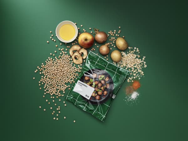 Eine Tüte des IKEA PLANTBULLAR zusammen mit den Zutaten wie Kartoffeln, Zwiebeln und Apfel.