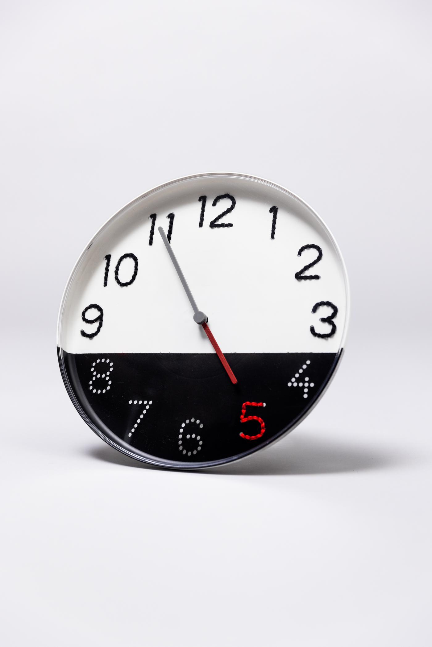 Eine Uhr die zur hälfte weiß und schwarz ist liegt auf einer weißen Oberfläche