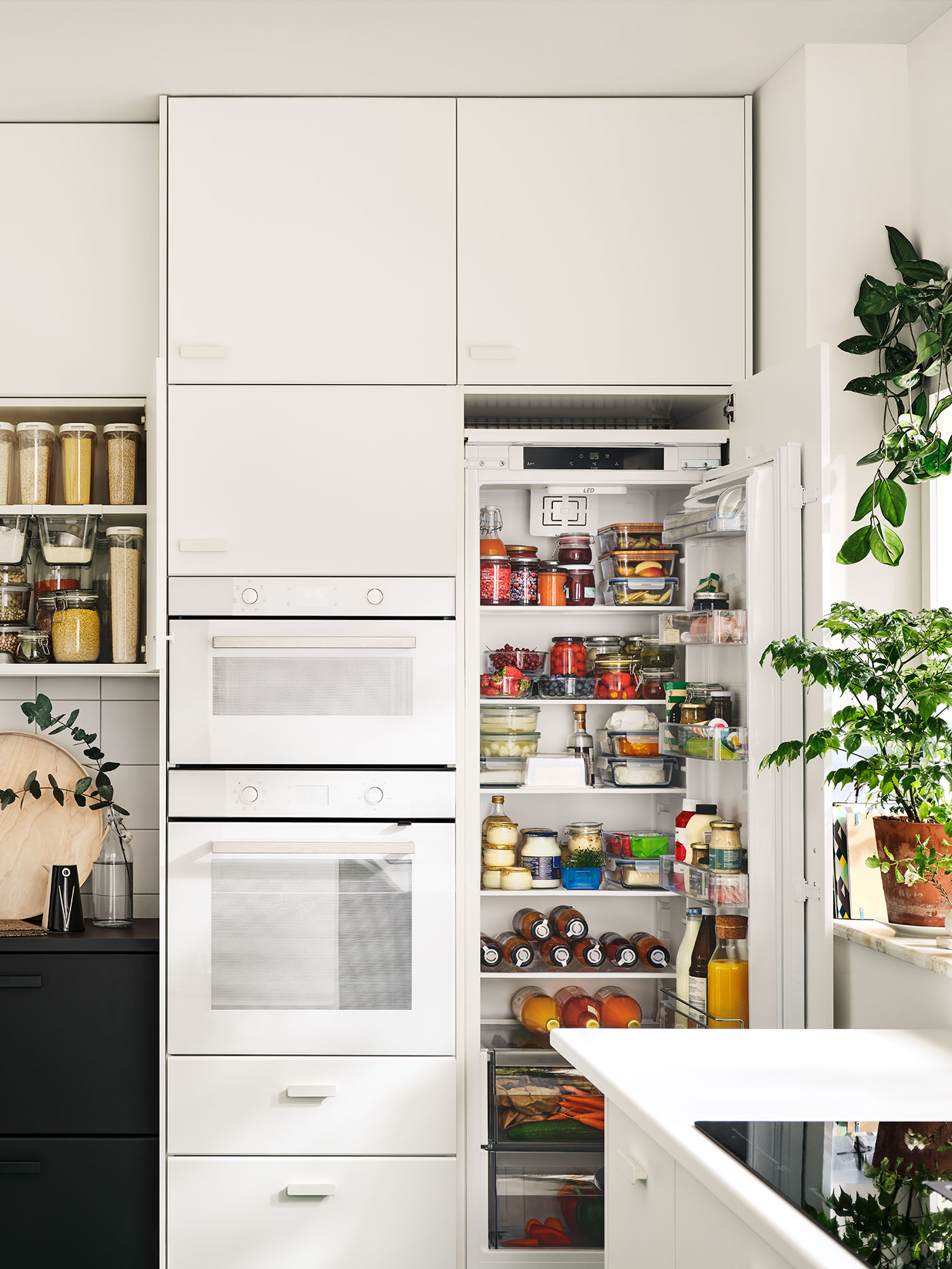 Eine weiße METOD Küche mit offenem Kühlschrank, der viele Aufbewahrungsmöglichkeiten und Ordnung zeigt.