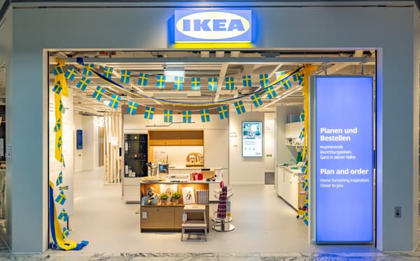 Eingang des IKEA Planungsstudios in St.Pölten, geschmückt mit kleinen schwedischen Flaggen. Im Inneren ist eine moderne Kücheninsel zu sehen.