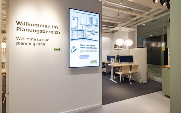 Eingang zum Planungsbereich im IKEA Planungsstudio. An der Wand steht „Willkommen im Planungsbereich“ mit einem großen Bildschirm, der zur Küchenplanung einlädt. Im Hintergrund sichtbare Beratungsplätze mit Computern.
