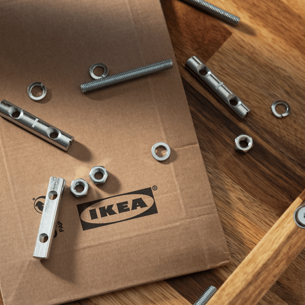 Einige Schrauben und kleine IKEA Ersatzteile liegen auf einem IKEA Versandkarton.
