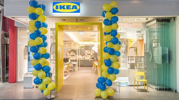 Einladender Eingang des IKEA Planungsstudios in Villach, dekoriert mit gelben und blauen Luftballons in den typischen Markenfarben. Im Inneren ist ein modern gestalteter Showroom mit Möbeln und Wohnaccessoires zu sehen. 