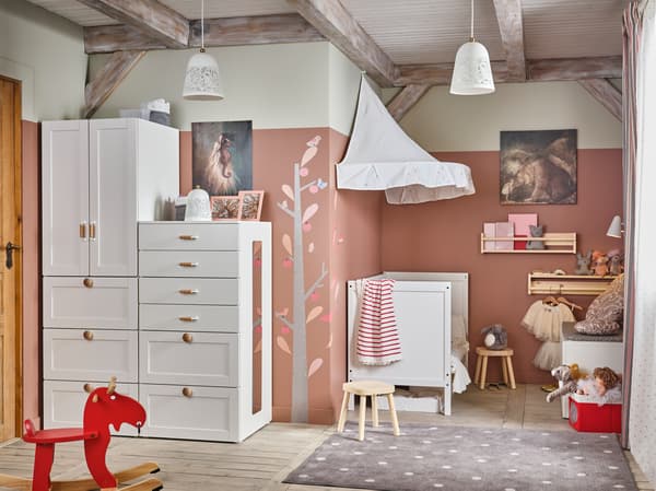 Einrichtungsidee für ein Kinderzimmer in Weiß/Rosa mit einem Kinderkleiderschrank und einem Babybett mit Betthimmel in Weiß im traditionellen Stil und einem roten Schaukelelch.