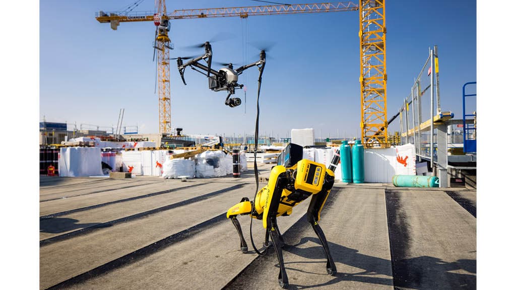 Einsatz von Robotik auf einer Baustelle: Vierbeiniger Roboterhund und Drohne mit Kamera im Einsatz zwischen Baukränen und Baumaterialien 