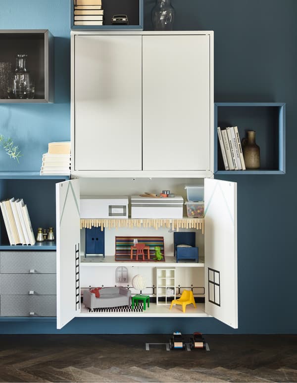 EKET cabinets mounted on the wall of a sophisticated living room are open to reveal the interior is a doll’s house.