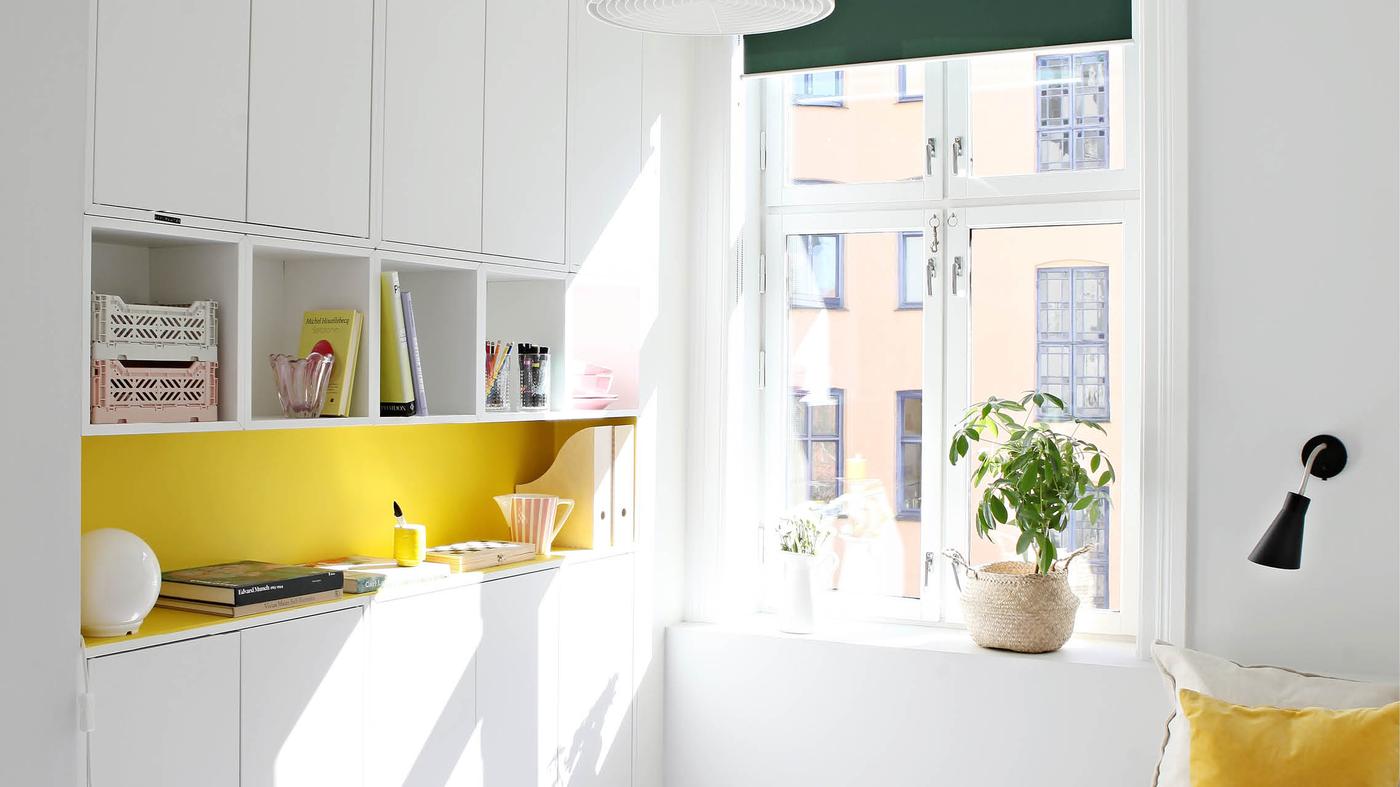 EKET hyller og skap i hvit montert lekkert opp på en gul vegg på et soverom.