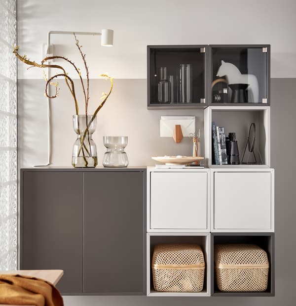 ชุดตู้เก็บของ EKET/เอียคเกท สีขาวและสีเทาพร้อมกล่อง SMARRA สองใบ แจกันแก้วสองใบ และของส่วนตัววางโชว์อยู่