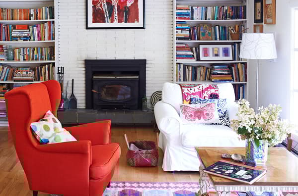 El brillante sillón rojo constituye un punto focal en este luminoso salón con suelos de madera natural y un distintivo en la decoración rústica.