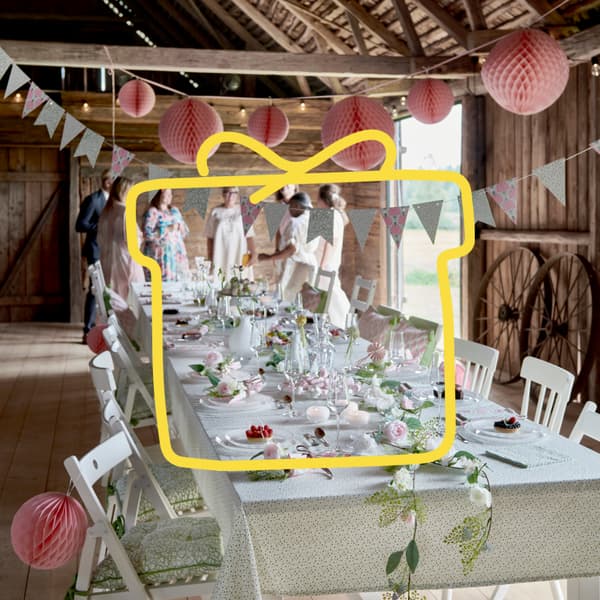 Elegancko udekorowana przestrzeń w stodole, w której stoi, długi, biały stół.