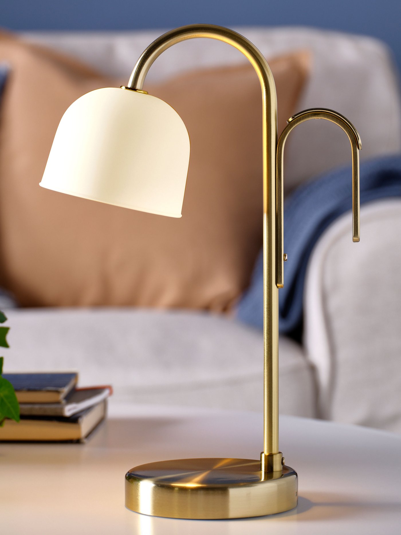 Elegant bordslampa med mässingsfot och vit lampskärm placerad på ett sidobord.