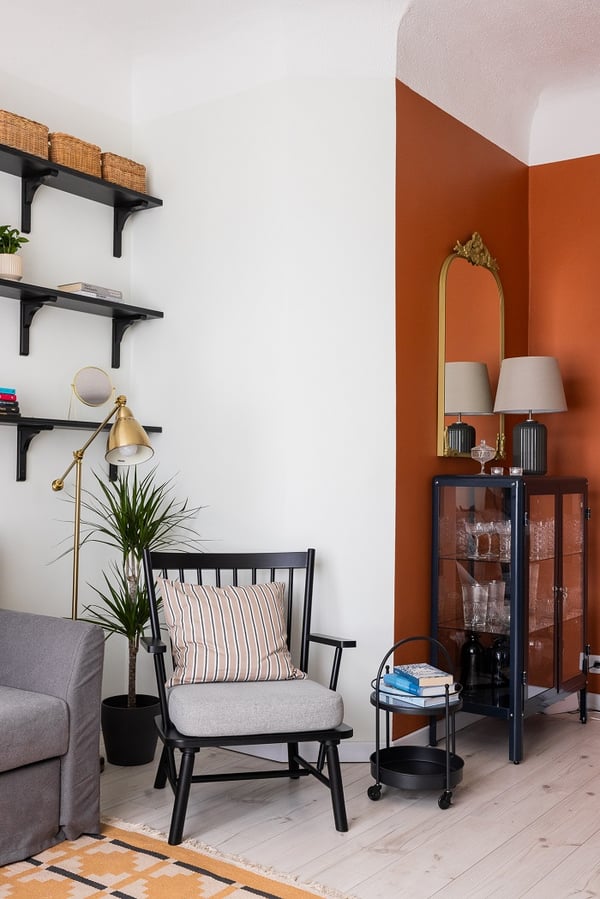 Elegant living room cabinet with glass doors, decorative mirror, and orange accent wall