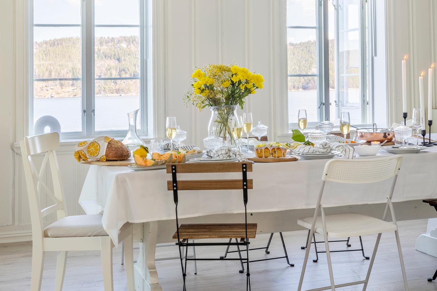 Elegant, white dining table with pasta plates, wine glasses and a fresh lemon as table decoration.