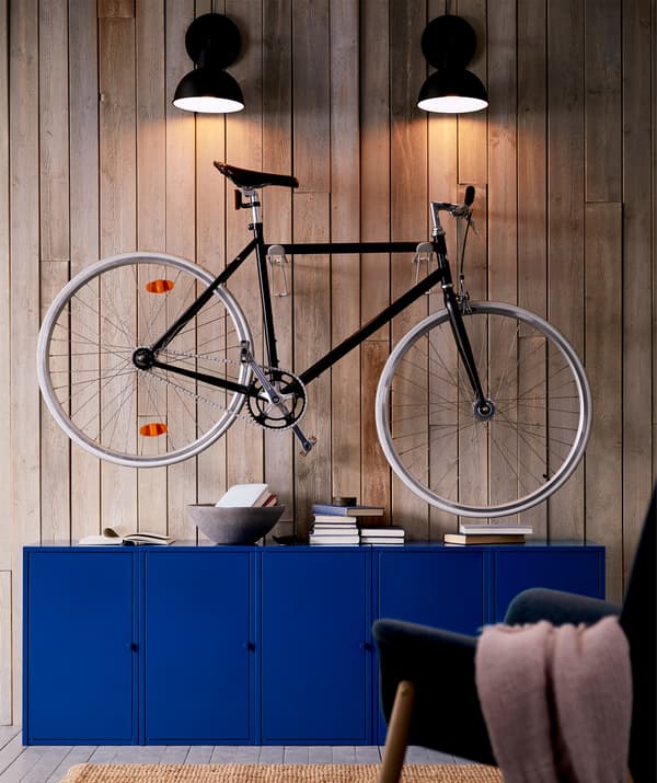 Elegante bici da città appesa sopra i mobili del soggiorno e illuminata dall'alto con delle lampade da parete.