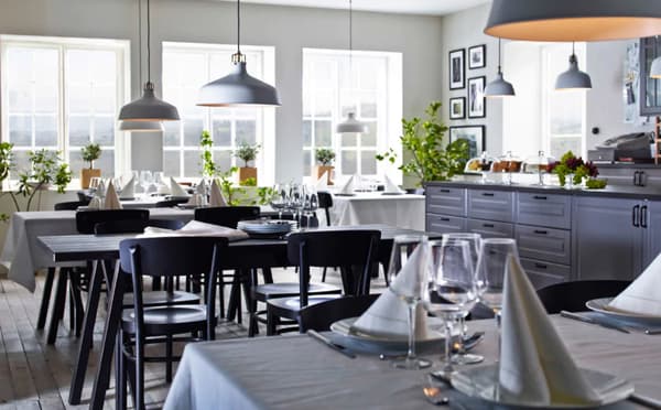 Elegantes Restaurant mit schwarzen GREBBESTAD/RYGGESTAD Tischen, GULLMAJ Tischdecke, Servietten & Weingläsern
