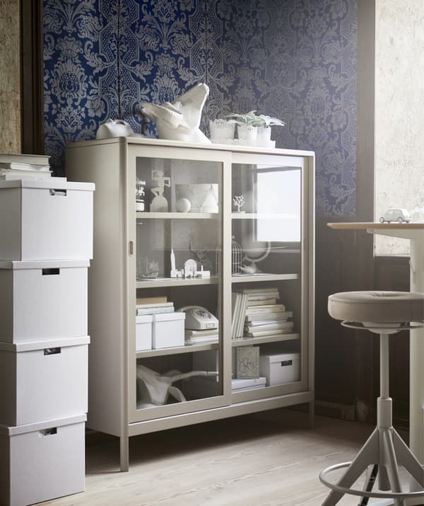 Élément beige à portes vitrées dans le coin d'un bureau décoré de papier peint bleu à motifs.