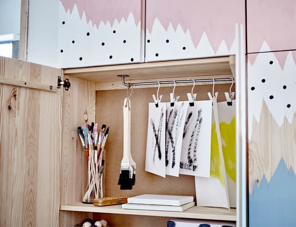 Éléments IVAR sur lesquels a été peinte une fresque en bleu, blanc et rose. Une des portes est ouverte pour montrer l’espace de rangement à l’intérieur.
