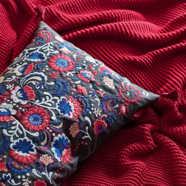 Embroidered folk cushion a with red bedspread