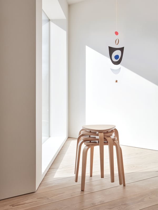 Empat bangku KYRRE yang dibuat menggunakan kayu birch dengan tempat duduk segi tiga dan kaki tirus ditindan dalam susunan berpintal.