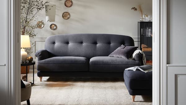 En antracit/brun to-personers ESSEBODA sofa står i en stue bag en døråbning.