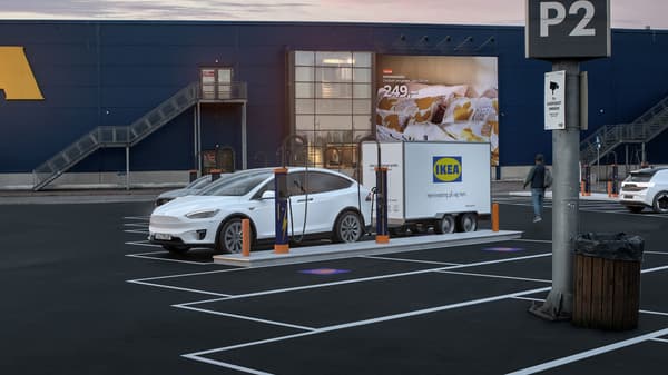 En bil med ett släp parkerad framför ett IKEA varuhus.