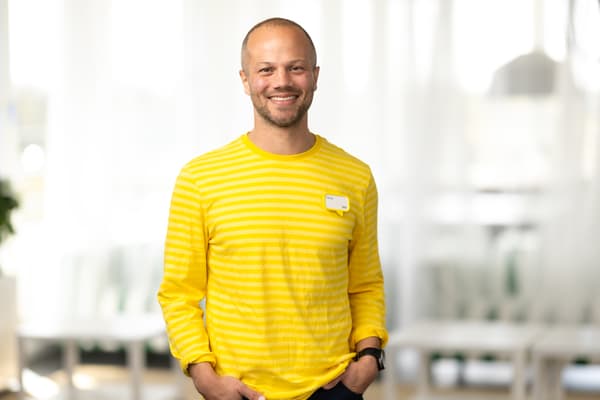 En bild på en IKEA medarbetare som står och ler.
