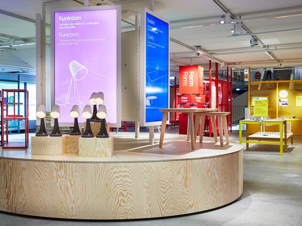 En bild som är tagen i IKEA Museumet i Älmhult som visar en läslampa framför en demokratisk design uppställning.