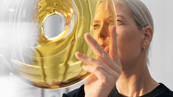 En blond kvinna håller i en gul munkformad lampa 