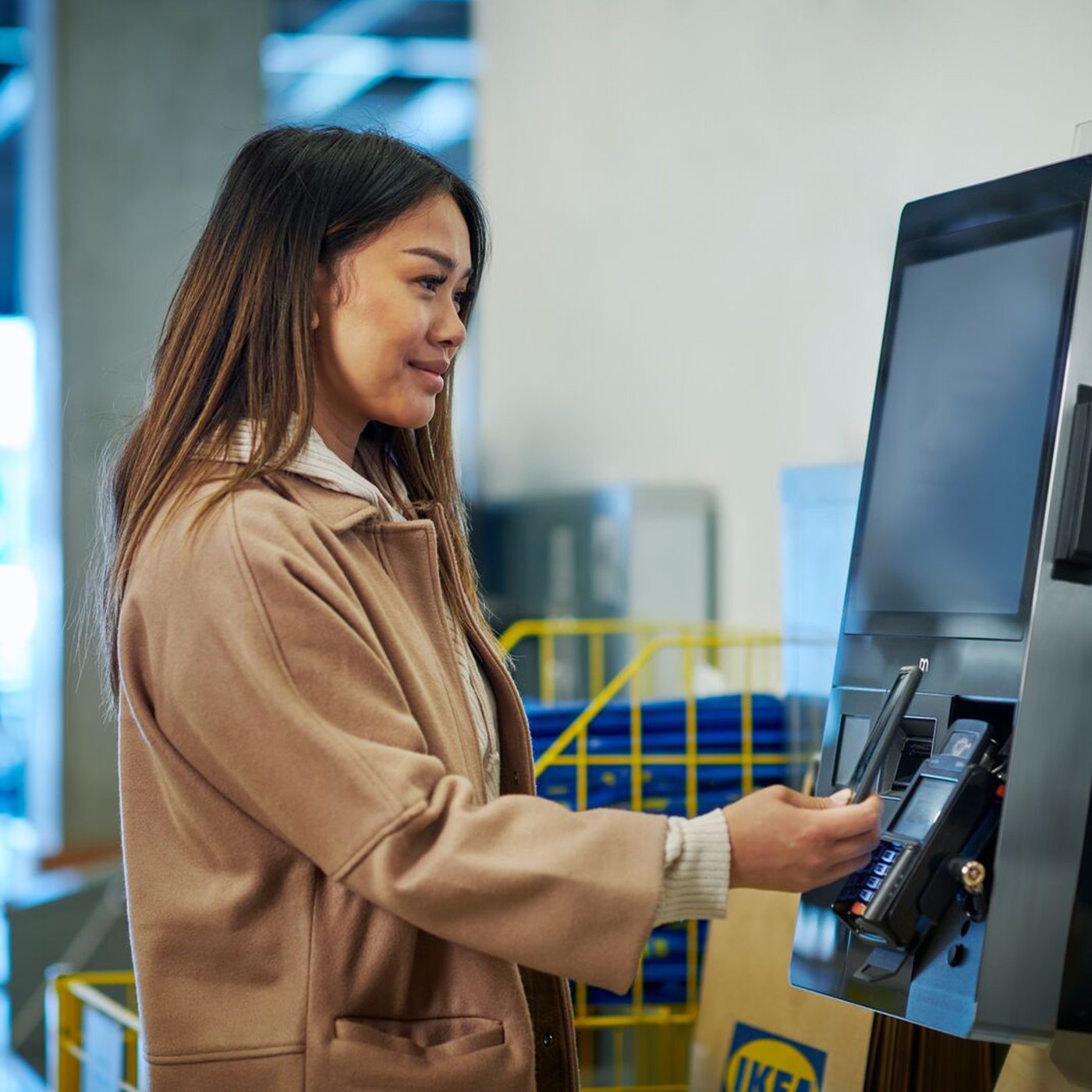 En dame står og checker ud på en scan selv terminal i et IKEA varehus.