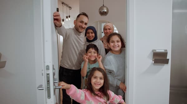 En familj om fem öppnar dörren till sin lägenhet.