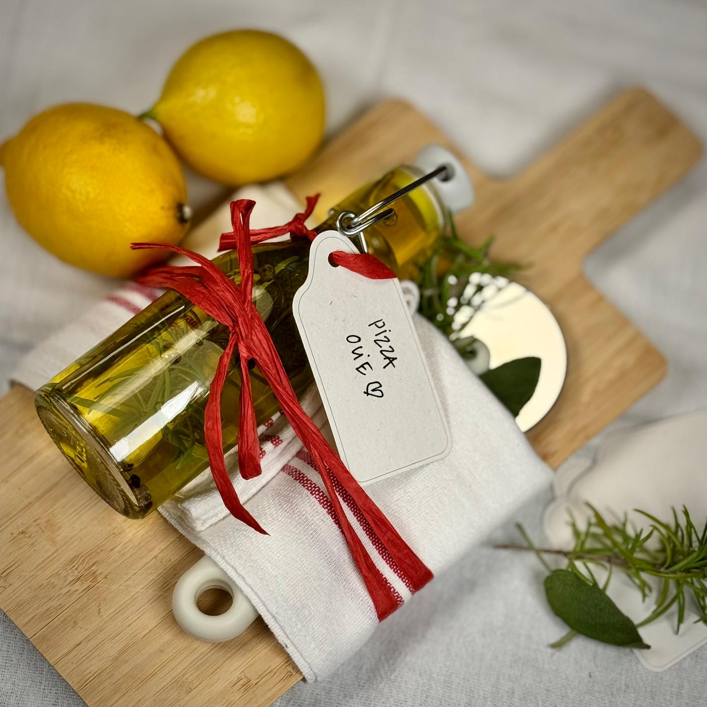 En flaske med krydderiolie samlet med et bånd som gave med et skærebræt og en pizzaskærer.