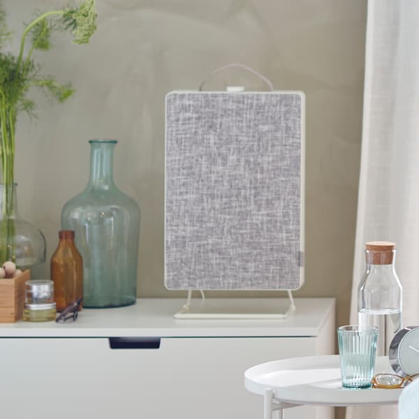 En FÖRNUFTIG luftrenser på en hvid kommode og et GLADOM bakkebord ved siden af med en IKEA 365+ karaffel og et glas på.