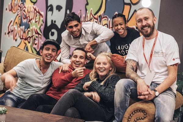 En gjeng av mennesker som sitter på en sofa og smiler.