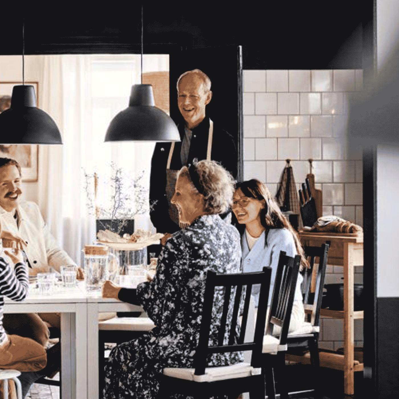 En gruppe mennesker som smiler sitter rundt et spisebord. 