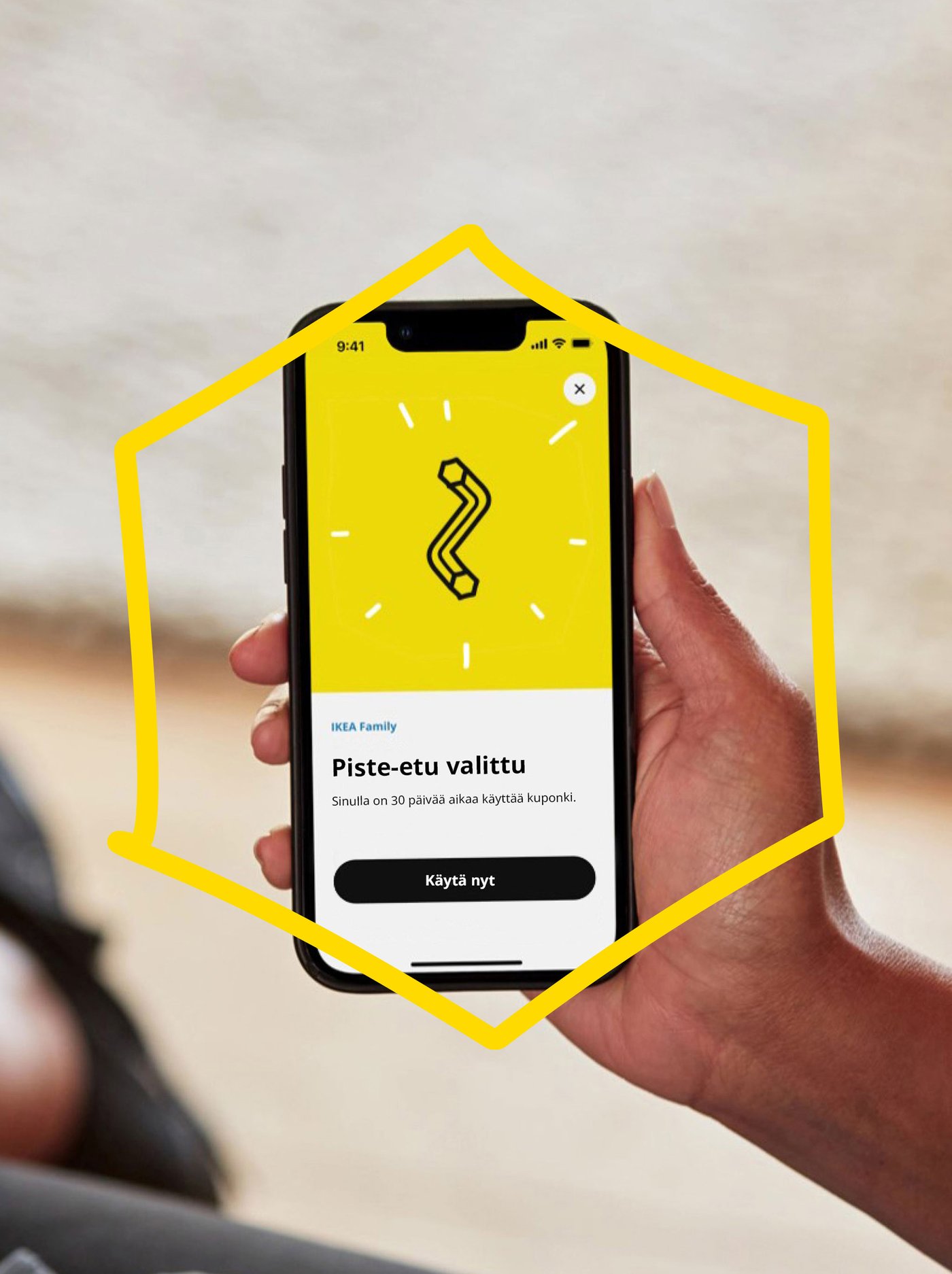 En hand håller i en telefon med en gul bakgrund och inloggningssidan till poängförmåner