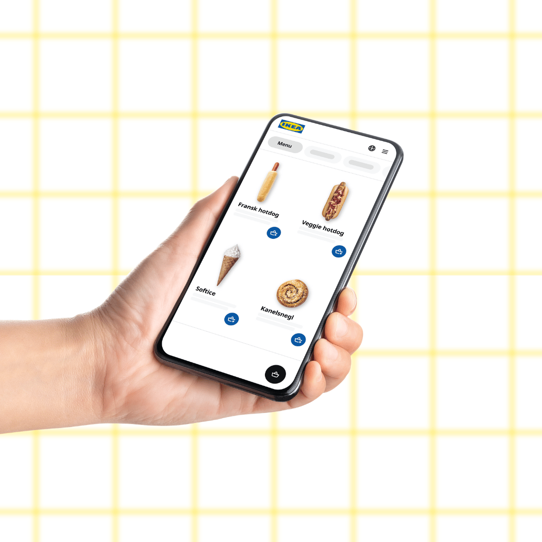 En hånd holder en telefon med ikea food mobile, hvor man kan bestille mad fra svansk bistro online