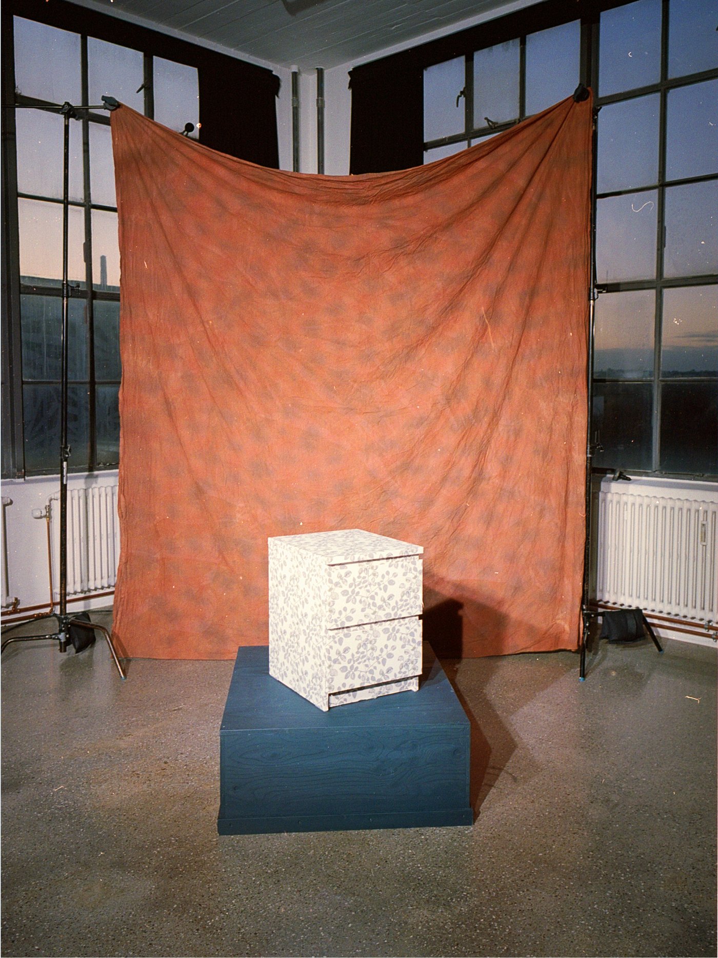 En hvid kommode foran et brunt bagtæppe og en del af FÖRNYA projektet hos IKEA.