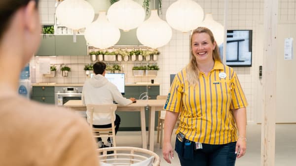 En IKEA medarbetare ler stort mot en kund.