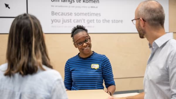 En IKEA medarbetare som hjälper två kunder med en retur.