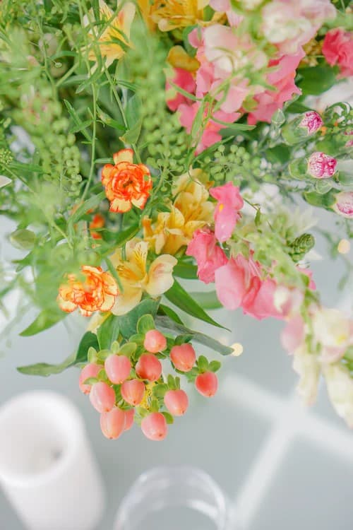 En KONSTFULL vase full av sommerblomster i ulike friske farger.