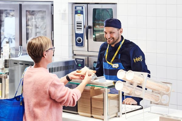 En kund som tar emot en korv i IKEA bistro.