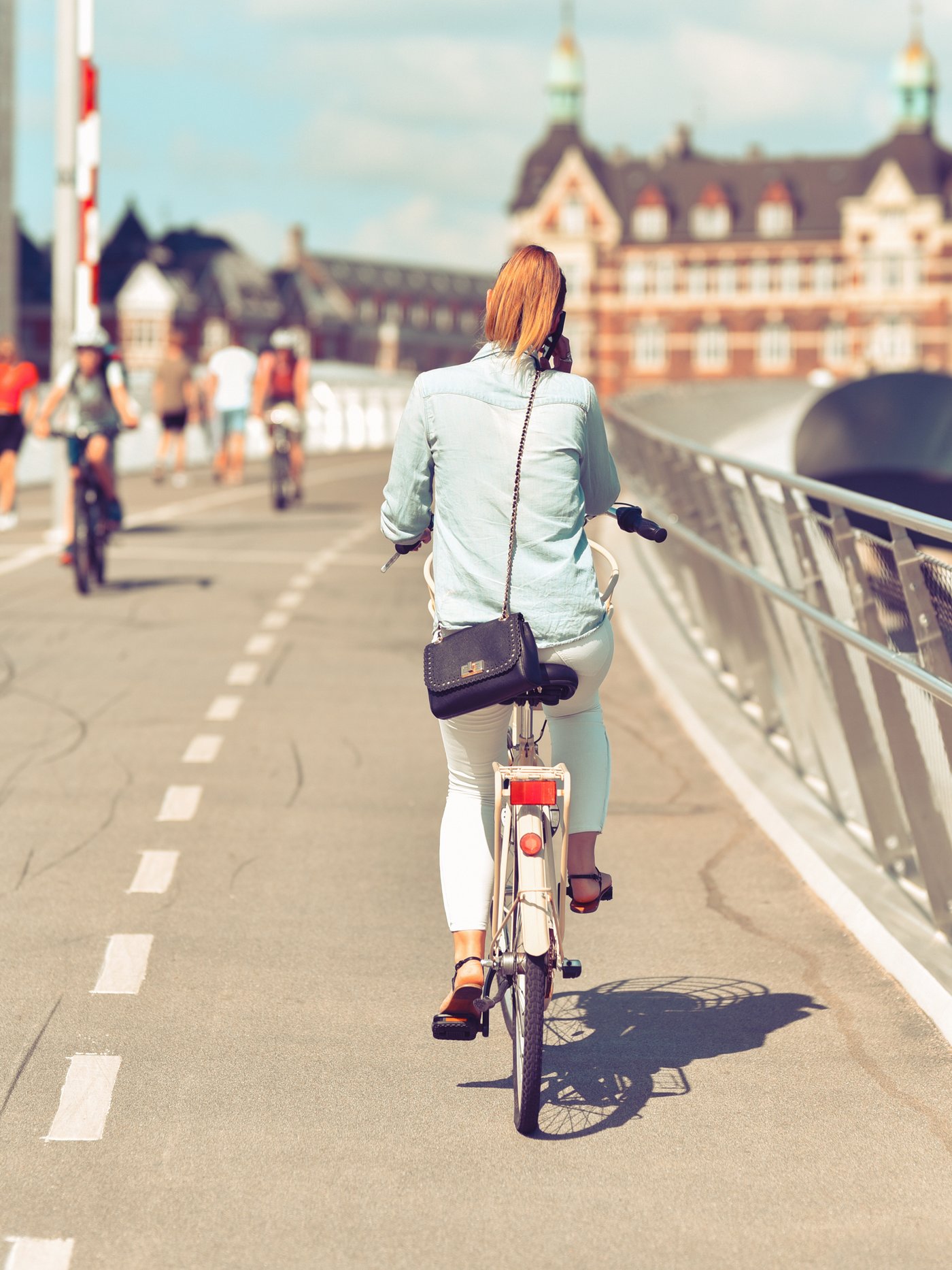 En kvinde cykler henover en bro.