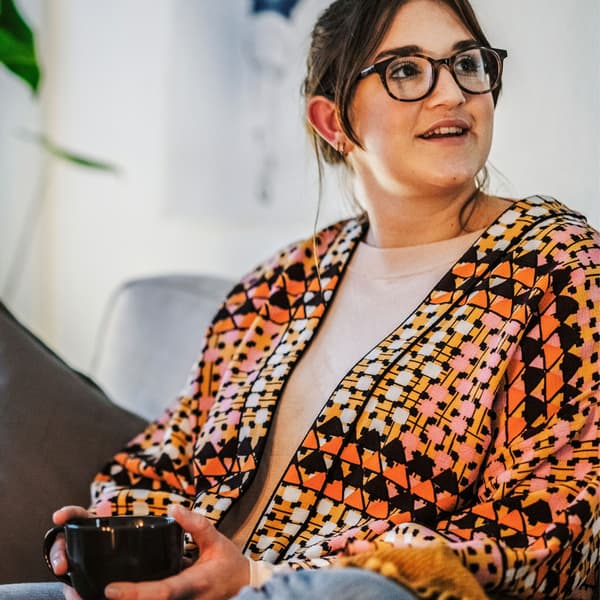 En kvinde sidder i en sofa med en kop 