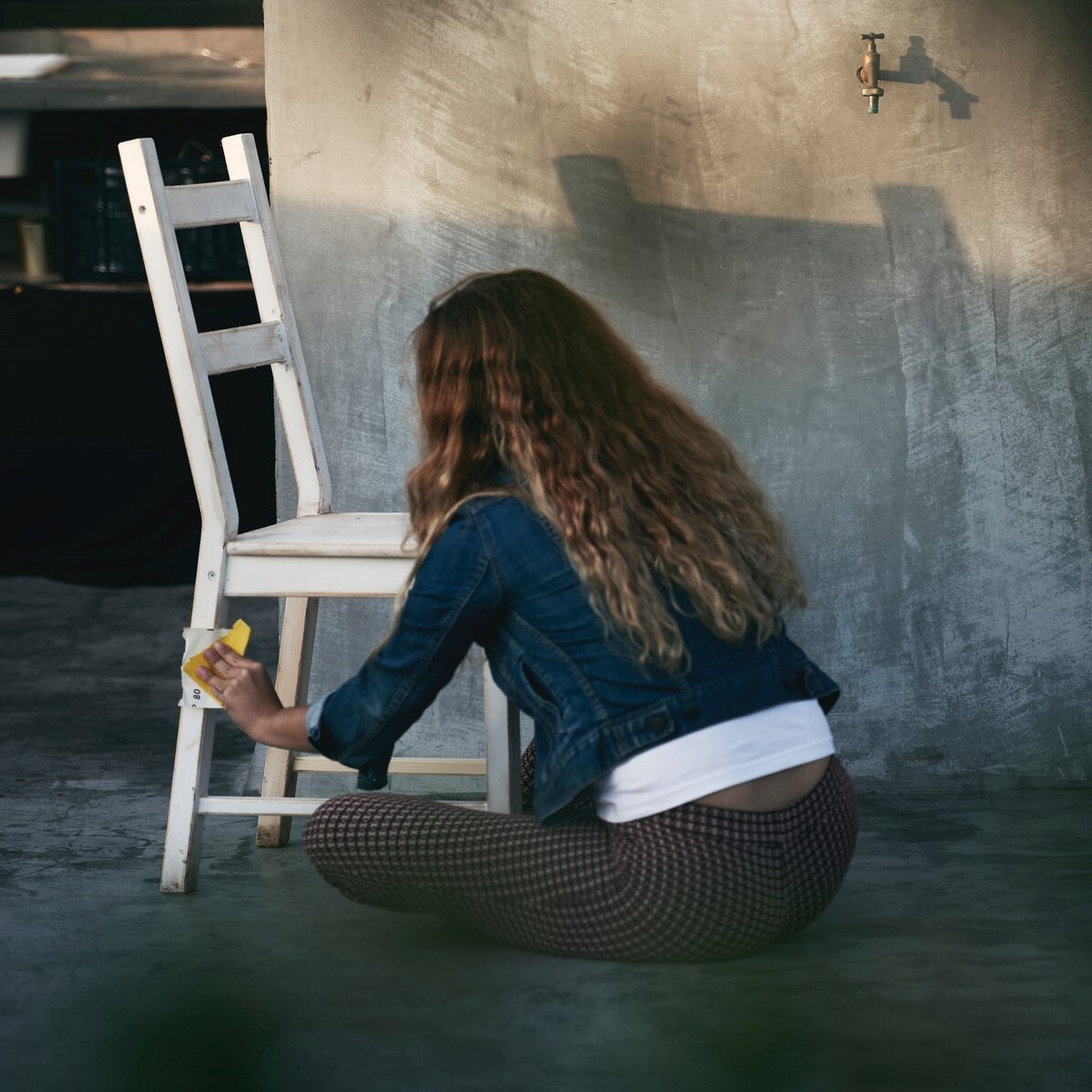 En kvinde sliber og istandsætter en stol.