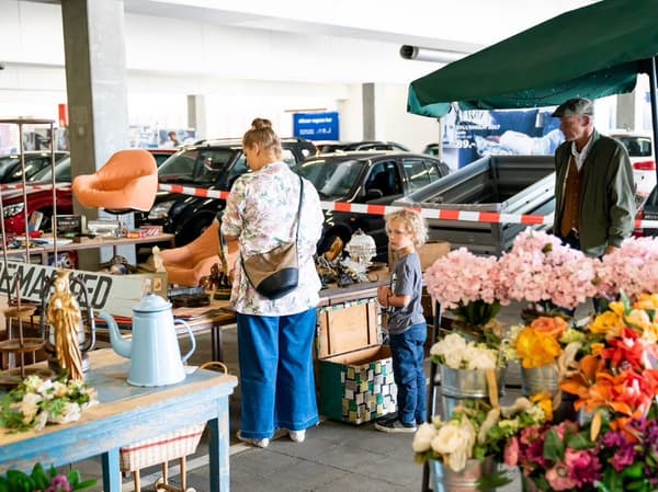 En kvinde står på et loppemarkede og kigger på hvad der sælges. 