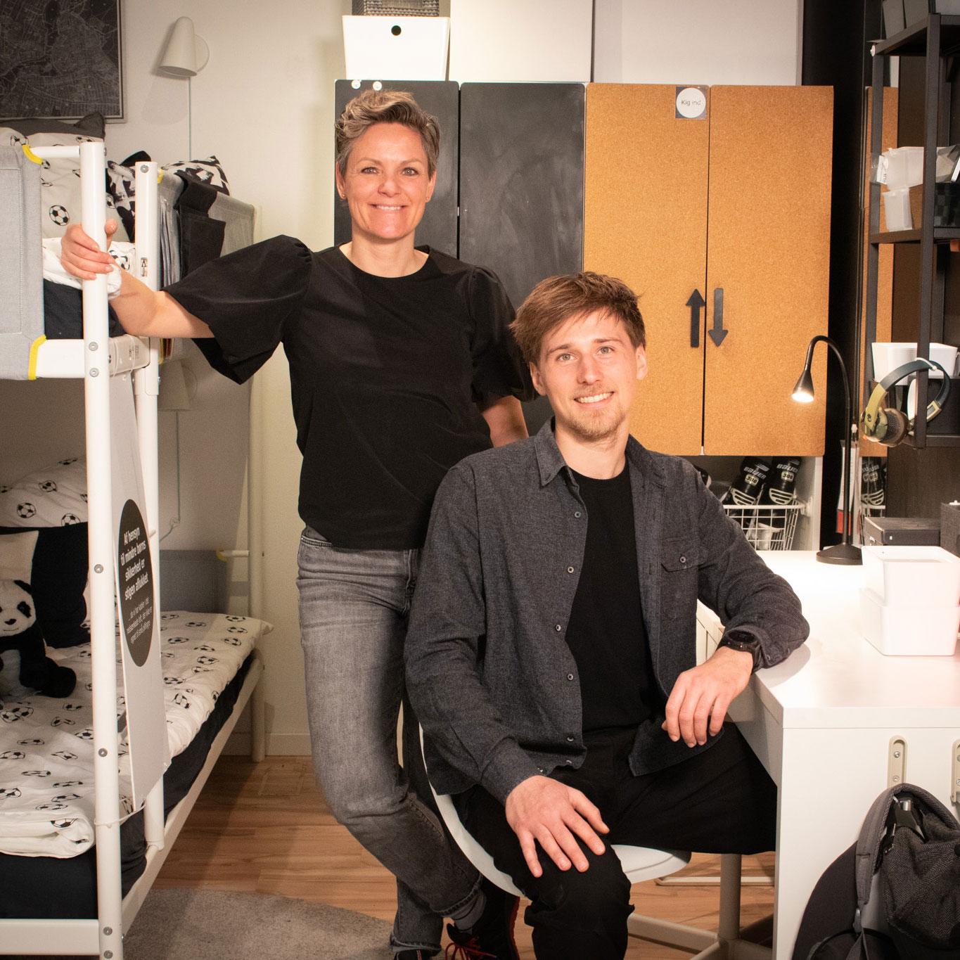 En kvinde står ved en køjeseng bag en mand ved et skrivebord på et børneværelse.